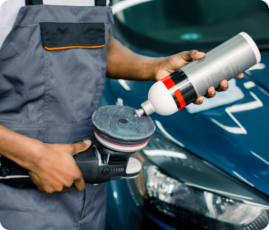 A person cleaning a car with a cleaning machine and a product. 