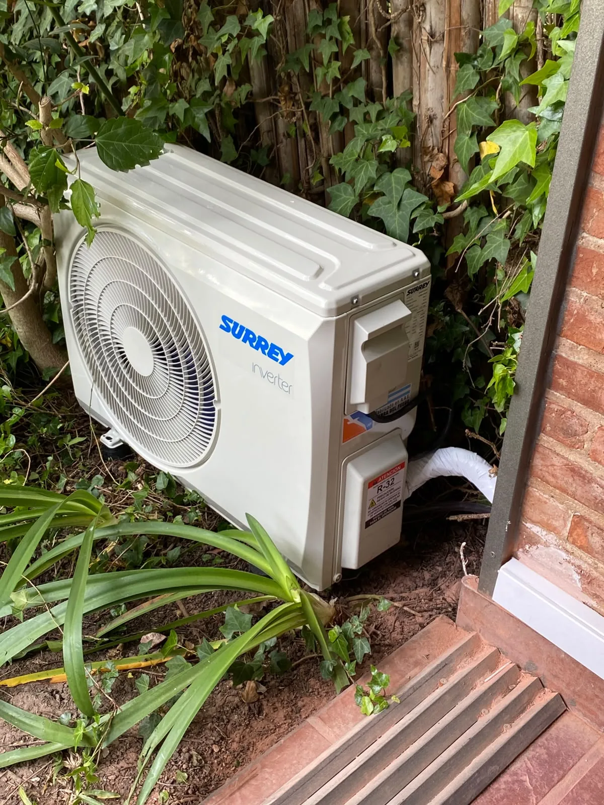 Unidad exterior condensadora de aire acondicionado instalada en un patio