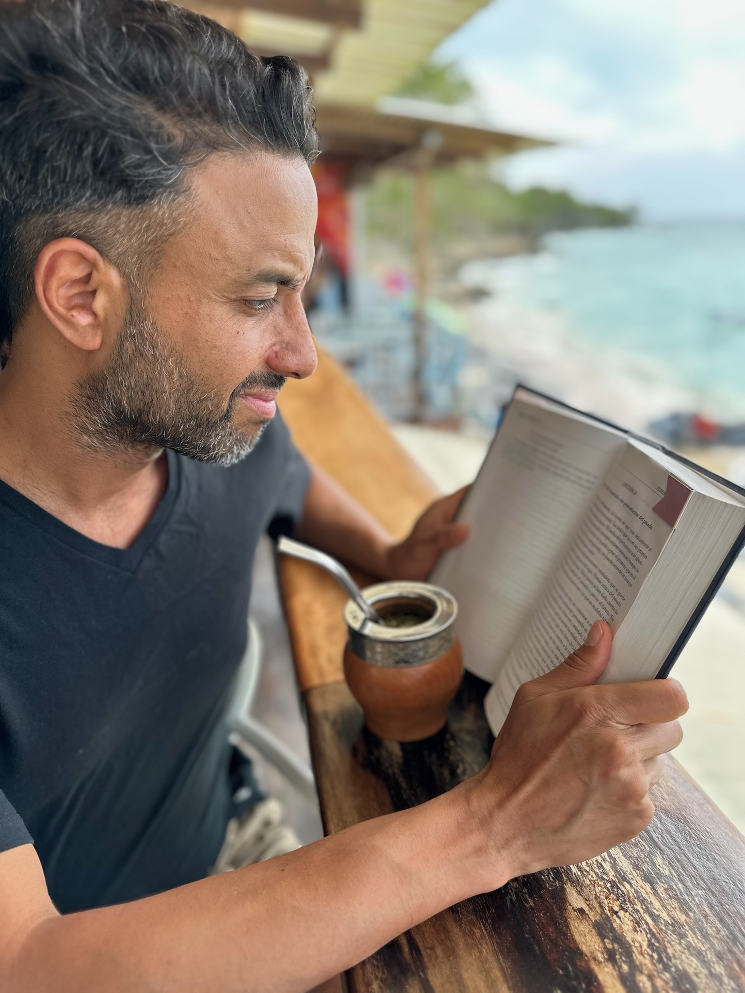 El Negro Monteiro leyendo Un Curso de Milagros frente al mar Caribe, con su mate al lado