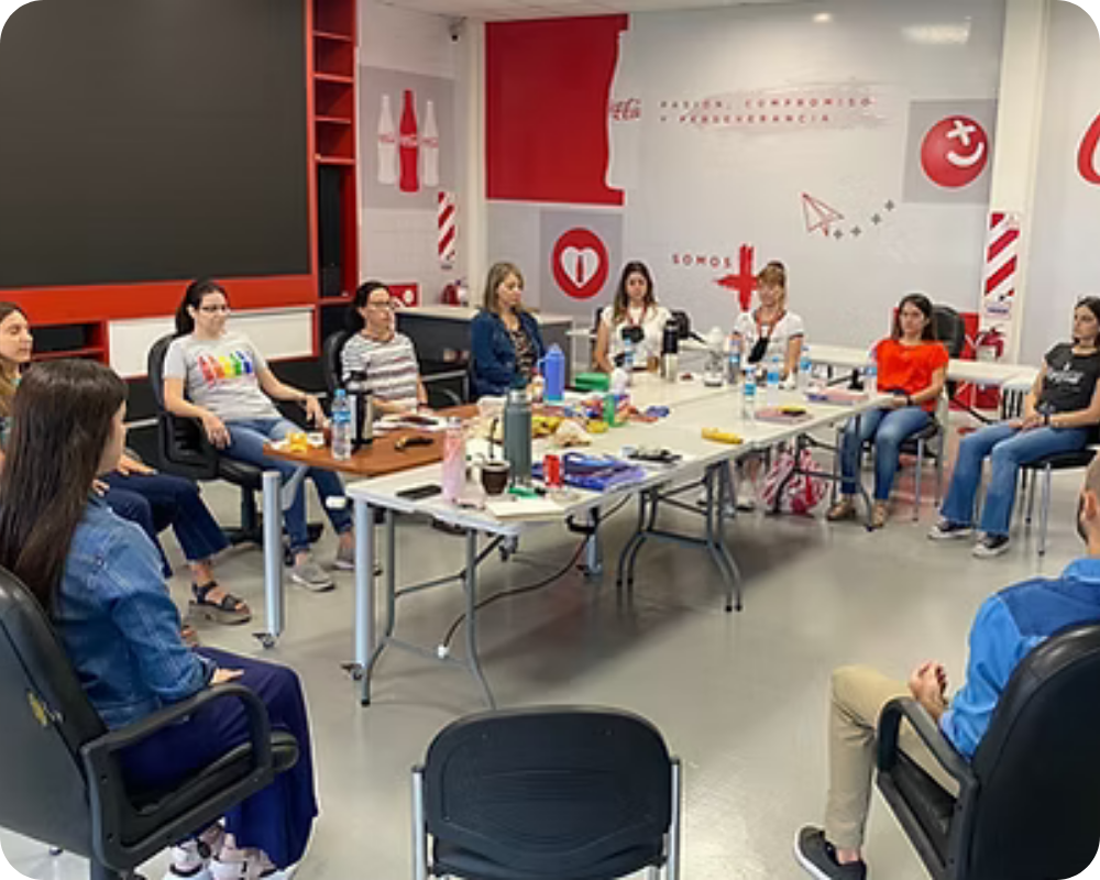 Un grupo grande reunido en torno a una mesa, en las instalaciones de Coca-Cola Andina, durante un taller