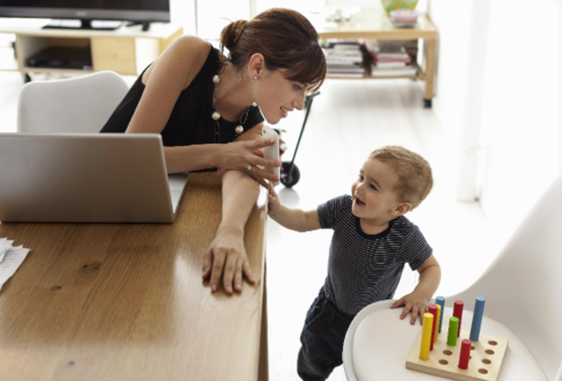 woman on computer wiht small child next to her woman on computer wiht small child next to her