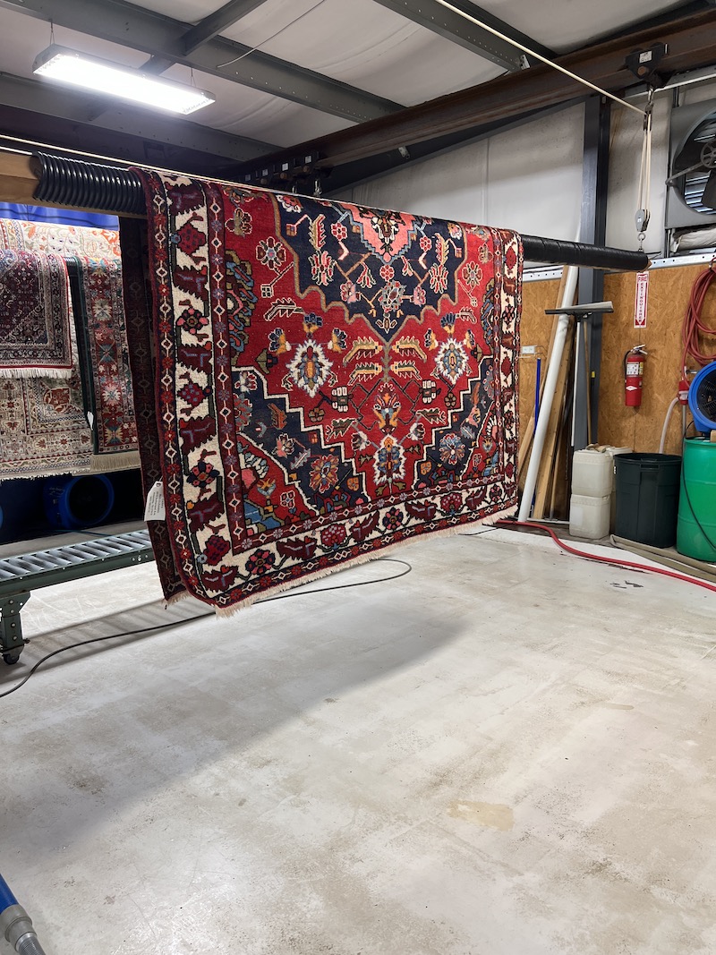 Professional rug drying facility, rugs hung on specialized drying racks