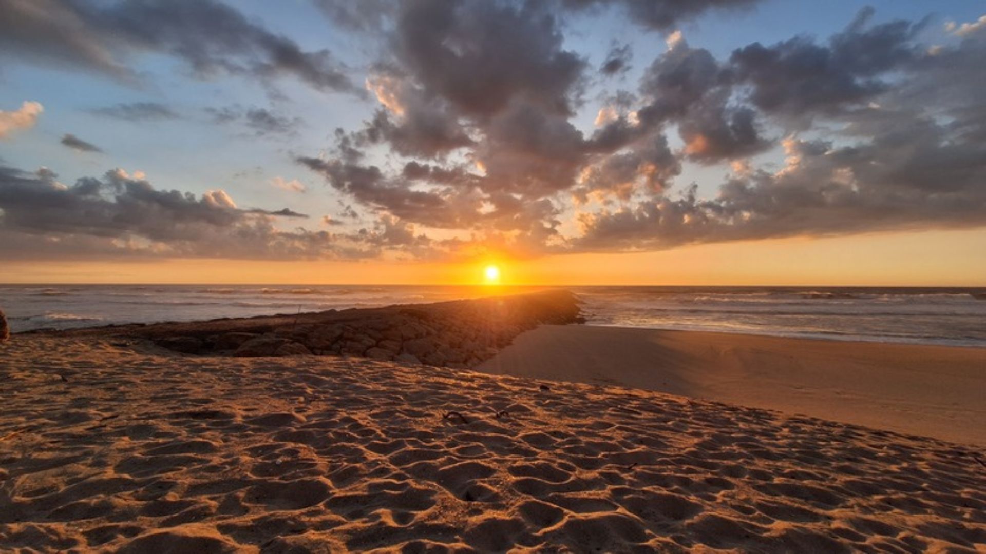 Sonnenuntergang an der Atlantikküste Portugals mit Sandstrand und Wellen während unseres Vanlife-Roadtrips.
