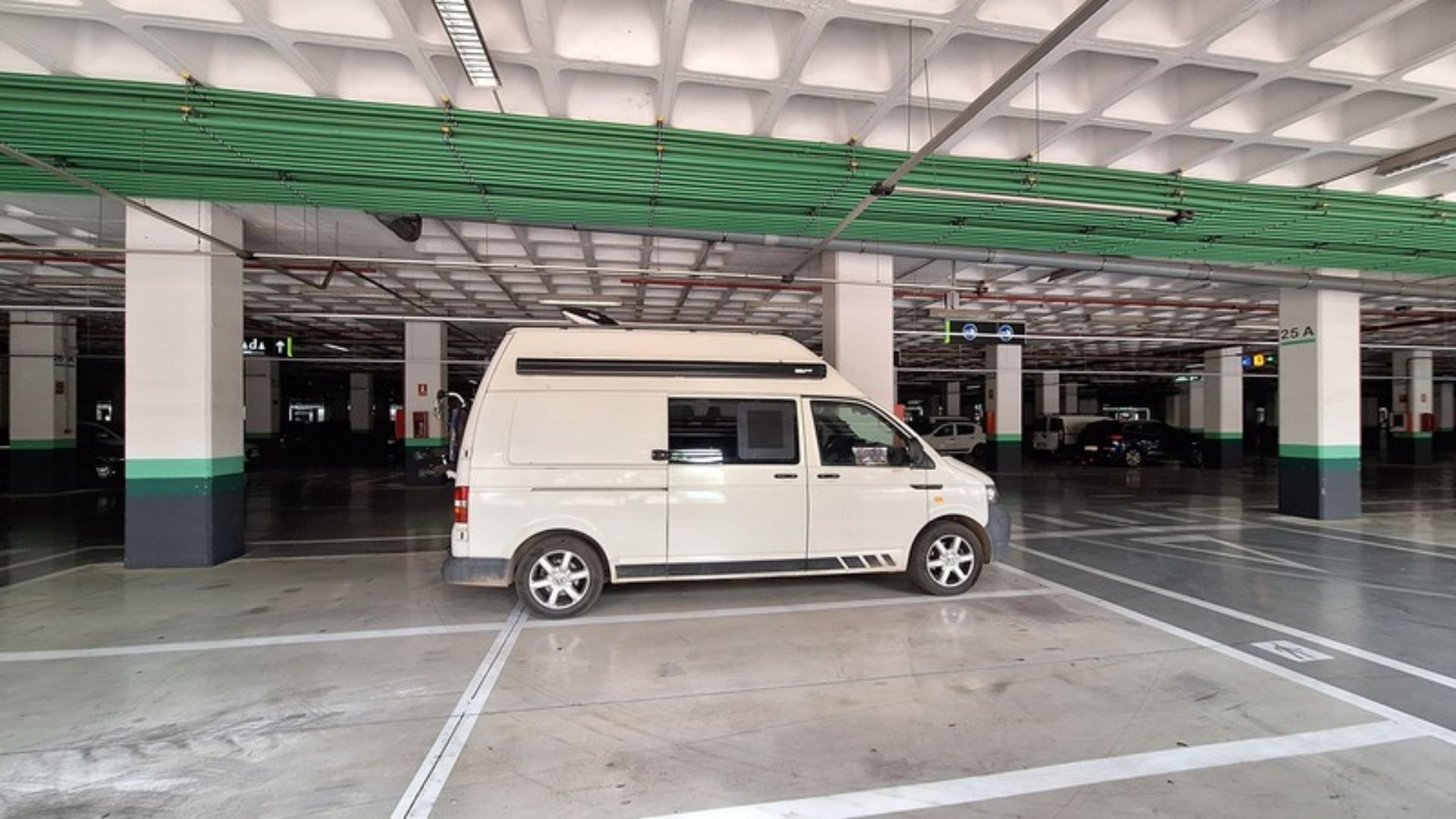 VW T5 Camper in einer Tiefgarage als schattiger Stellplatz bei Hitze – eine mögliche Alternative für kurze Aufenthalte, sofern Fahrzeughöhe und Regeln es zulassen.