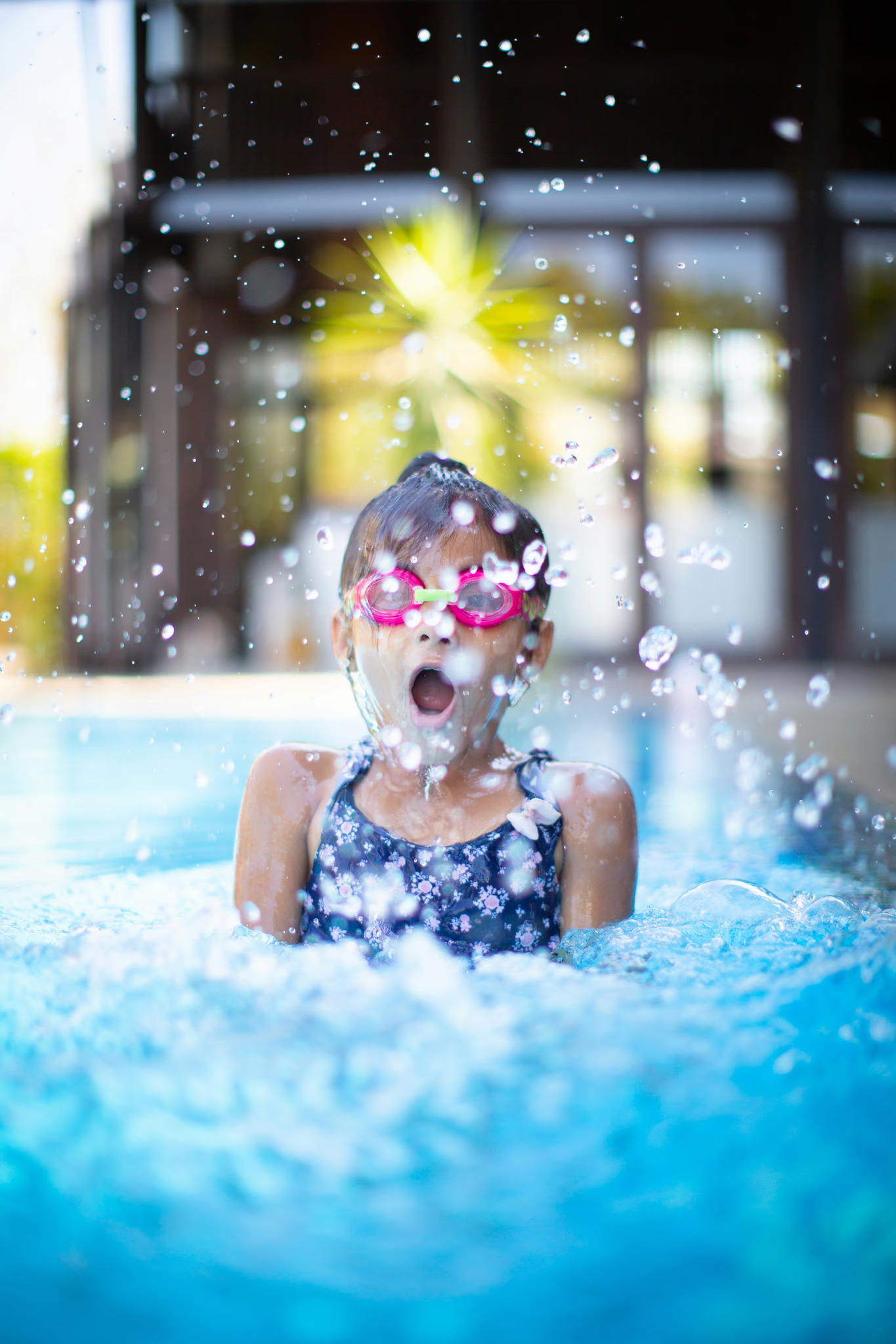 Young girl splashing joyfully in a swimming pool