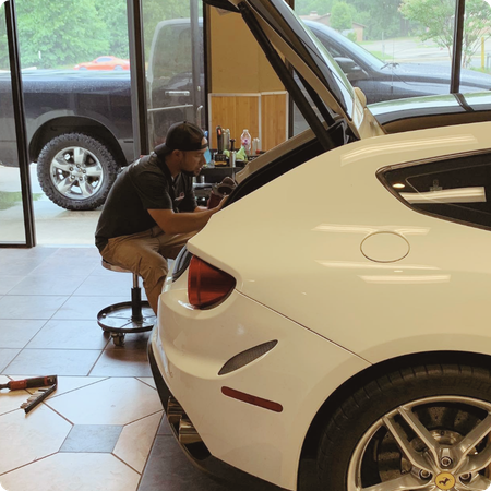 Technician removing dent from car hood panel