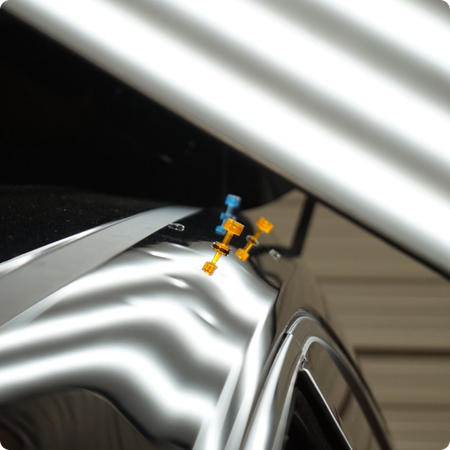 Technician repairing hail dents on car hood