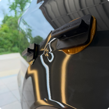 Technician removing dent from car hood panel