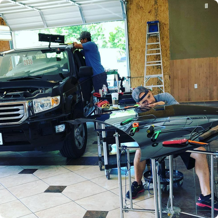 Technician removing dent from car hood panel