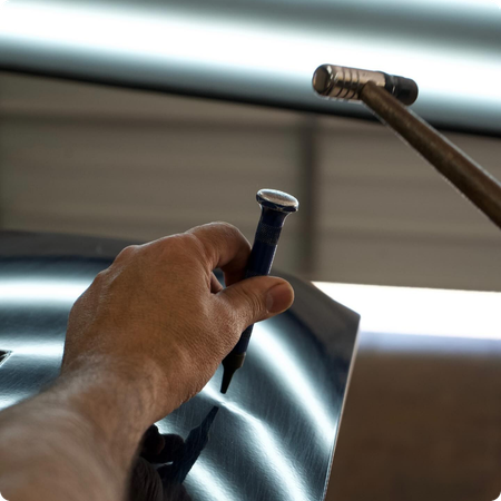 Technician repairing hail dents on car hood
