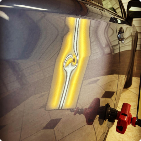 Technician removing door ding from vehicle panel