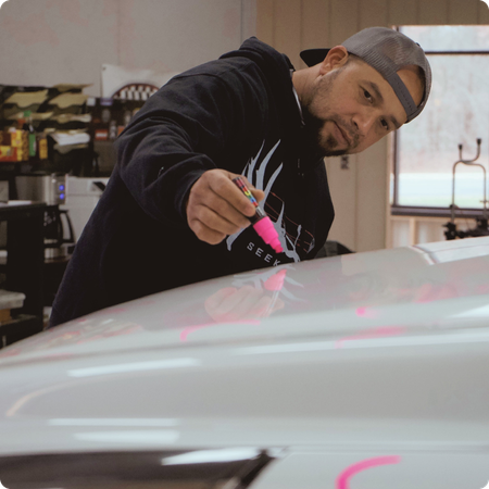 Paintless dent repair technician working on vehicle panel