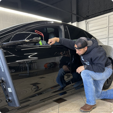Paintless dent repair technician working on vehicle panel