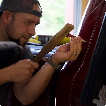 Paintless dent repair technician working on vehicle panel