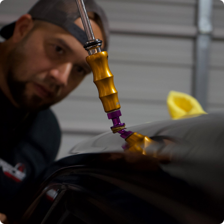 Paintless dent repair technician working on vehicle panel