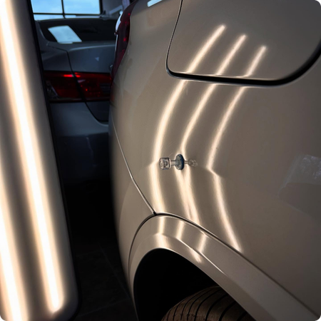 Technician repairing hail dents on car in Longview