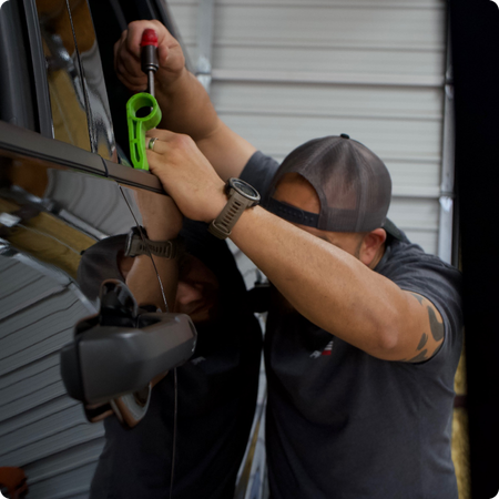 Technician using PDR tools on car door panel