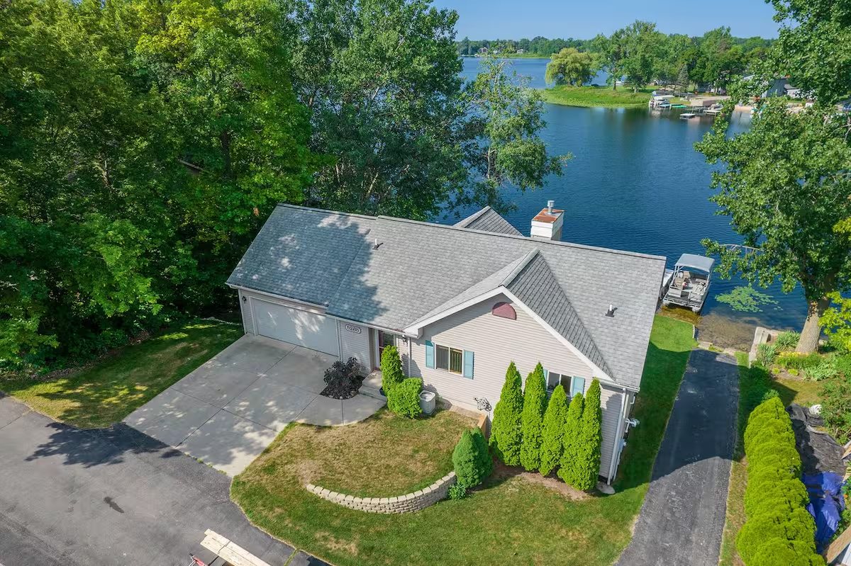 Cecily's lakefront short-term rental near Grand Rapids, Michigan, seen from the water with a dock and kayaks