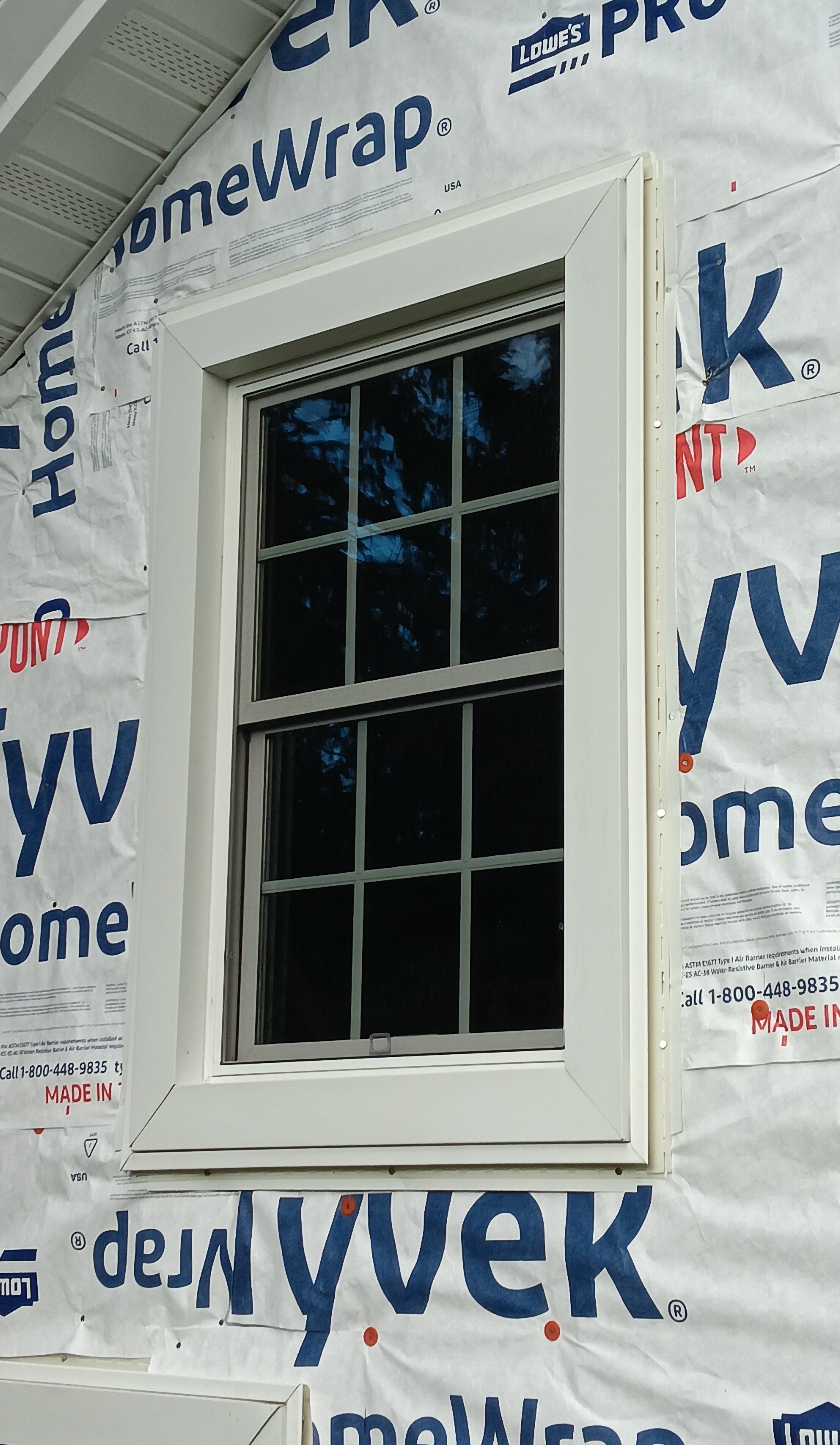 Close-up of a replacement window installation on a home, framed by durable Tyvek house wrap, ensuring energy efficiency and professional craftsmanship