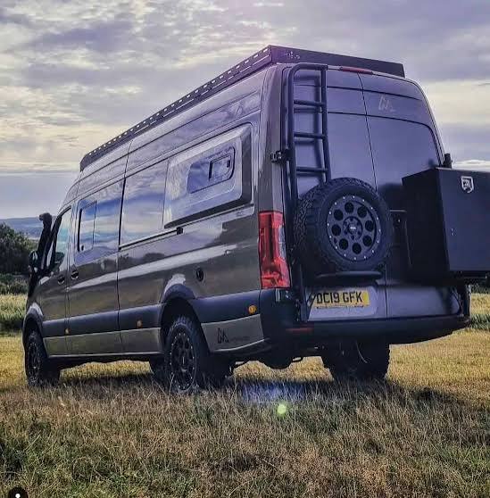 Rear-quarter view of a grey campervan with a side pod
