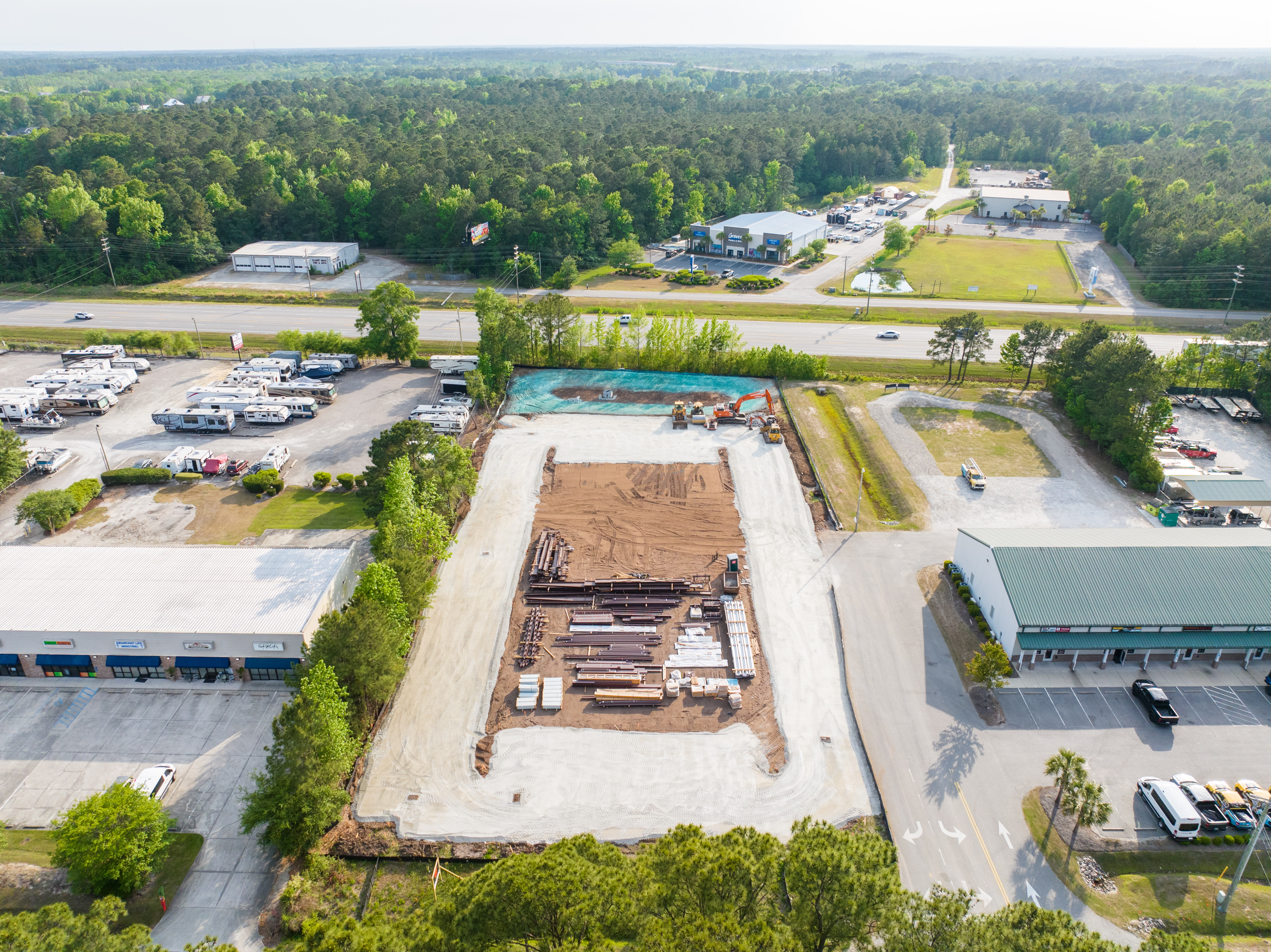 Close aerial of graded pad with steel materials staged on site