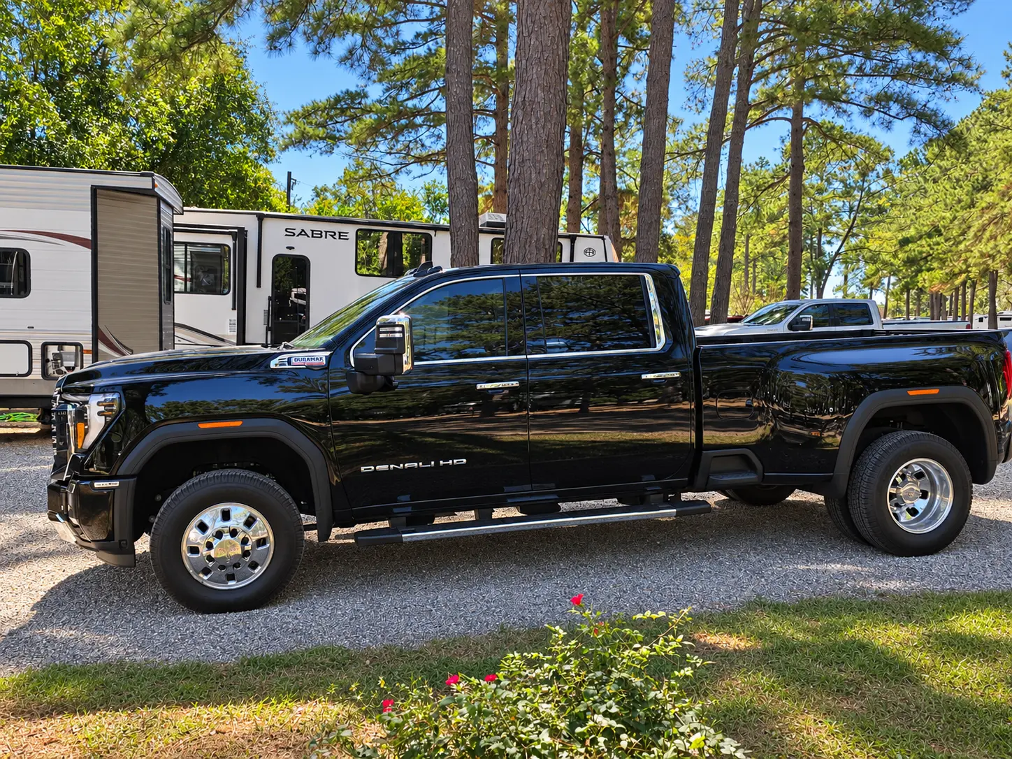 Happy Trails RV Transport’s black GMC Denali truck parked at a campground.