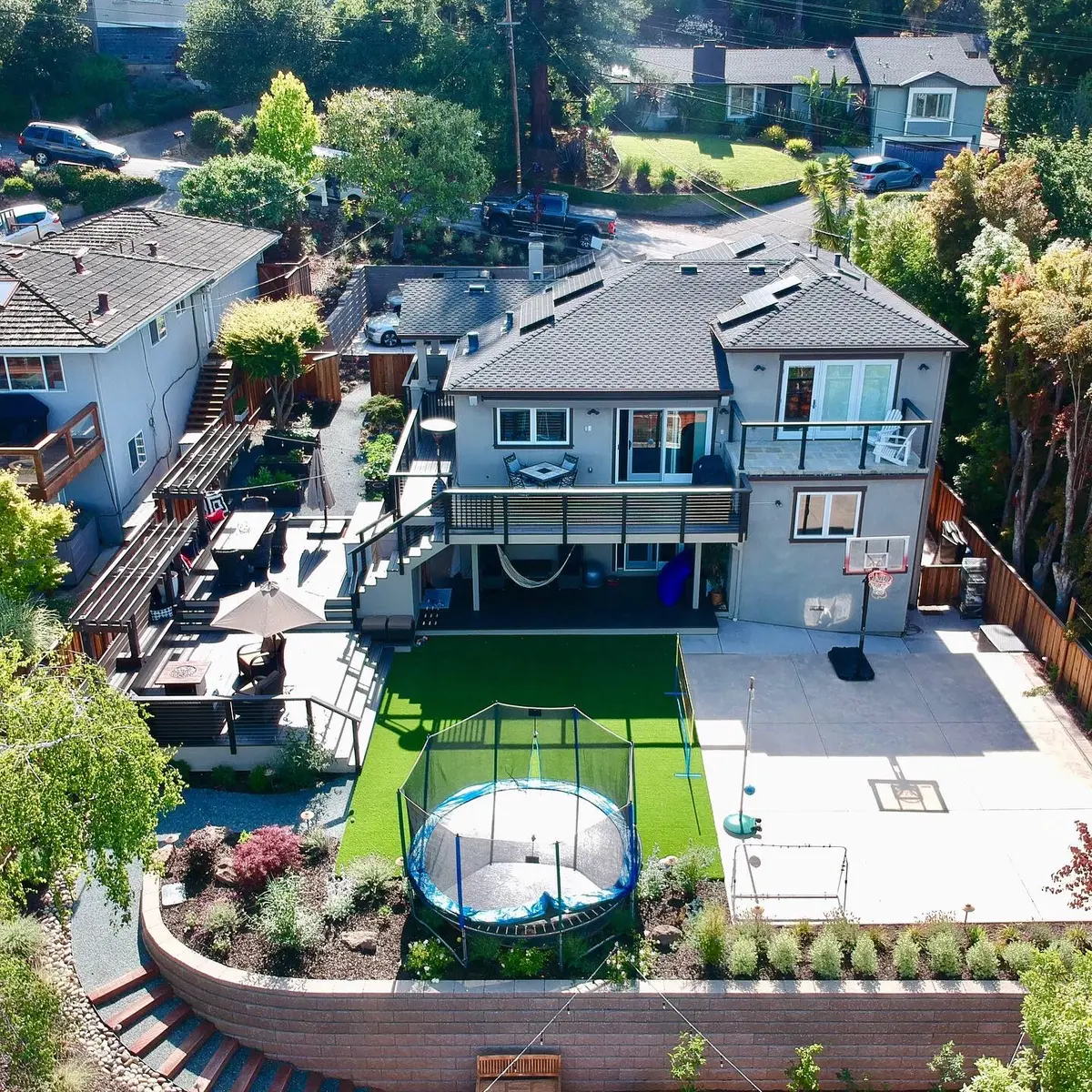 Aerial view of a finished backyard with multi-level decks, artificial turf, a concrete patio and planted beds
