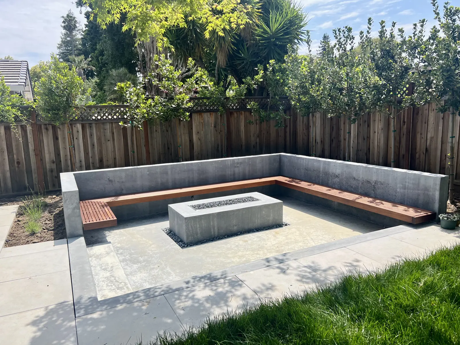 Built-in concrete bench with wood seating around a rectangular fire feature