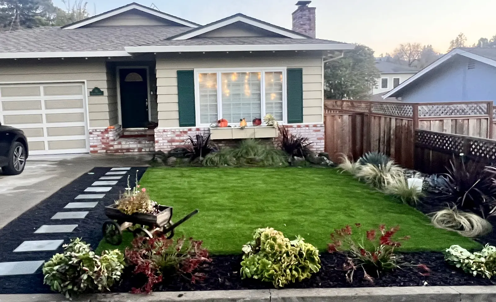 Front-yard landscaping with artificial turf, dark mulch and colorful planted beds