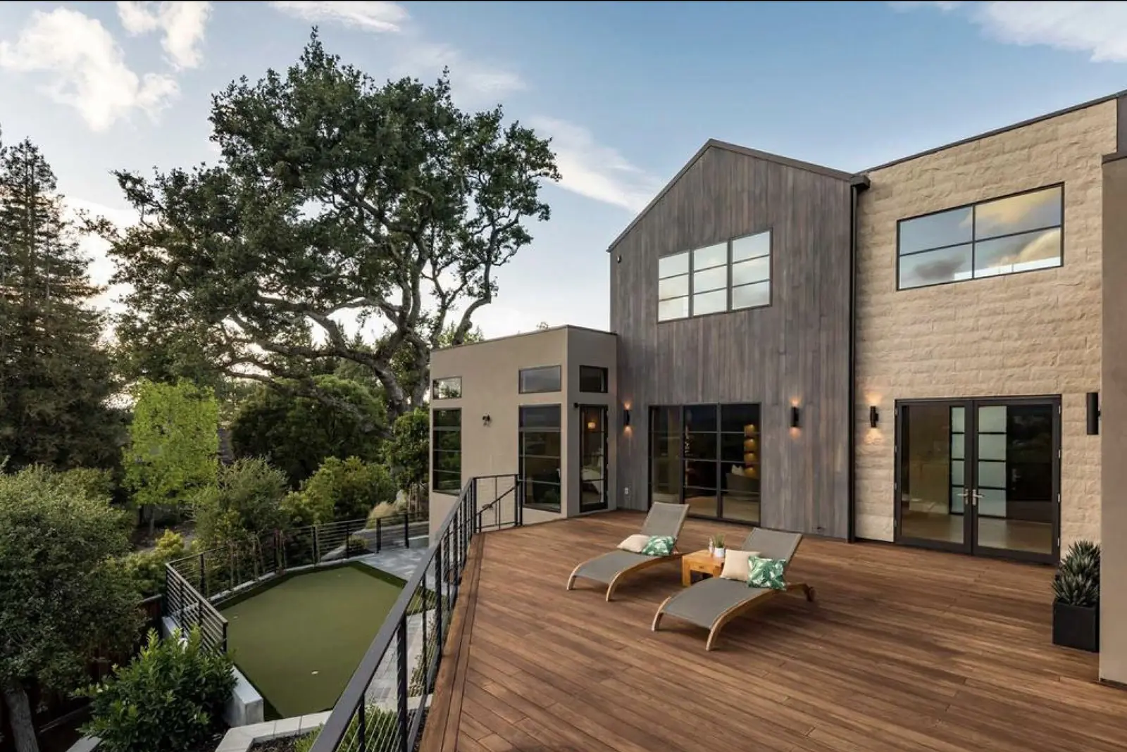 Modern backyard with a wood deck, artificial turf and a mature oak tree