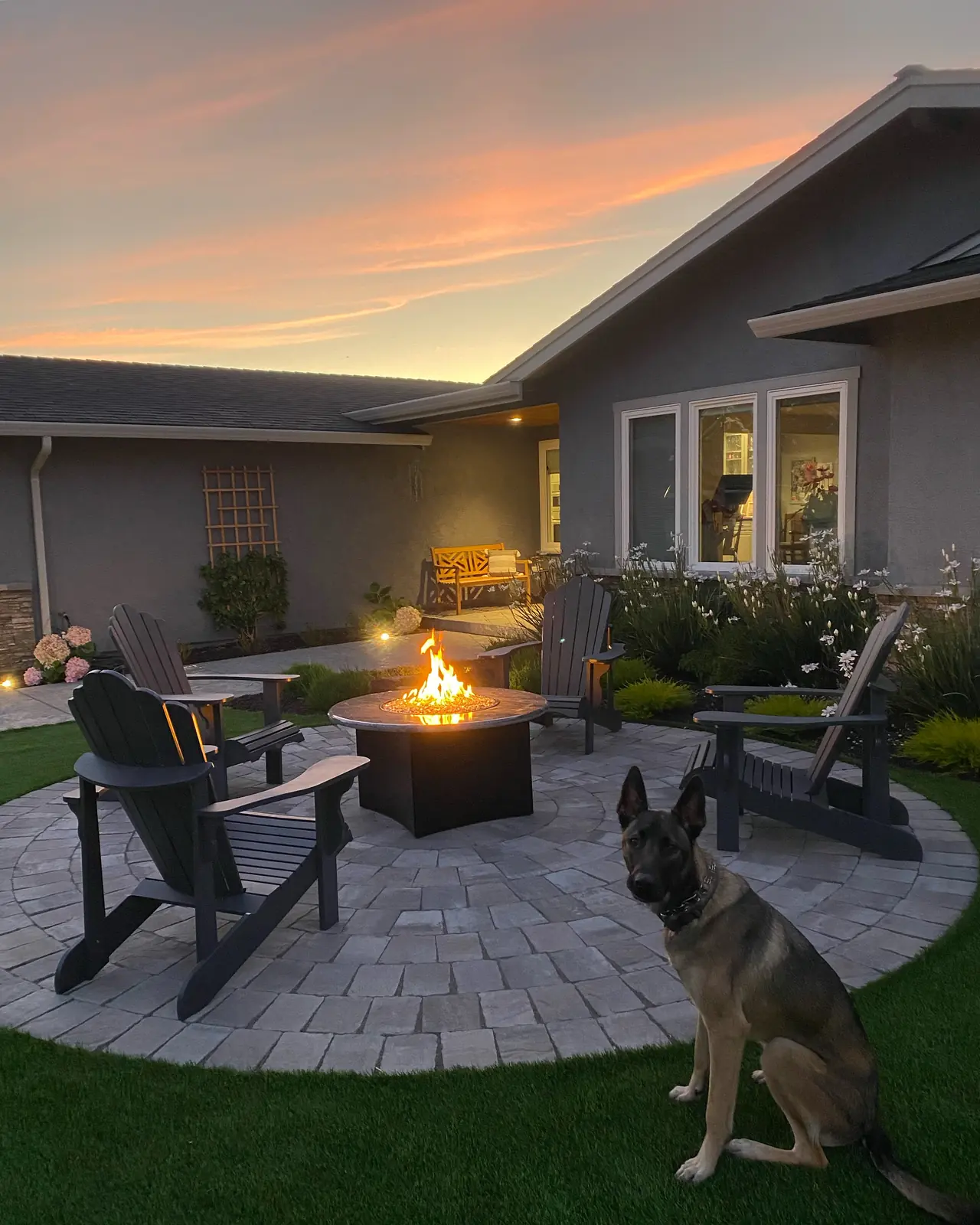 Circular paver patio with a fire pit and outdoor chairs at sunset