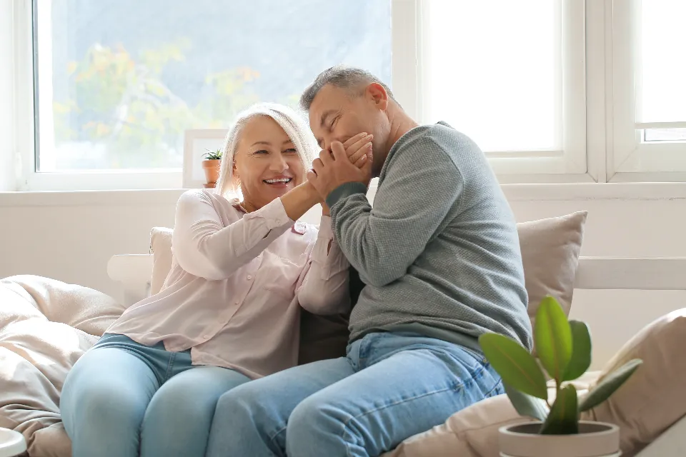Couple laughing together on the sofa in their sunlit, freshly painted living room