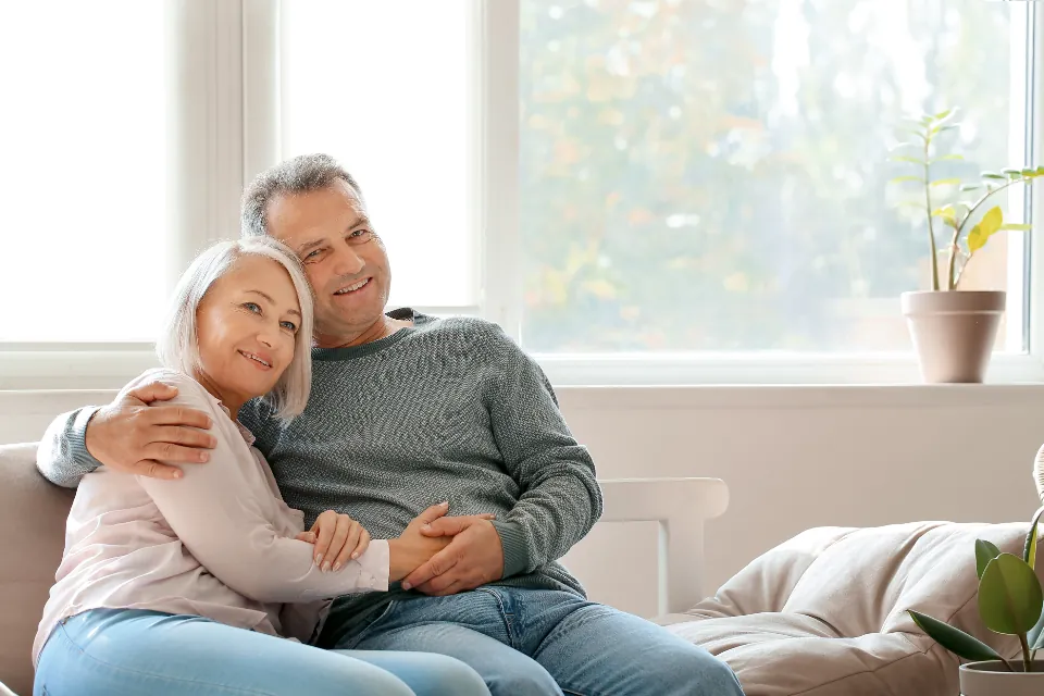 Smiling couple hugging on the sofa in a bright, airy living room