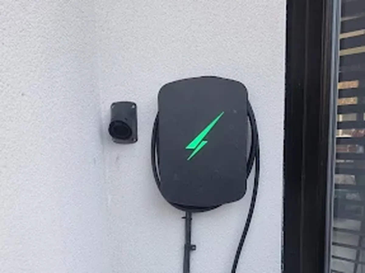Wall-mounted EV charger with its cable on a rendered wall