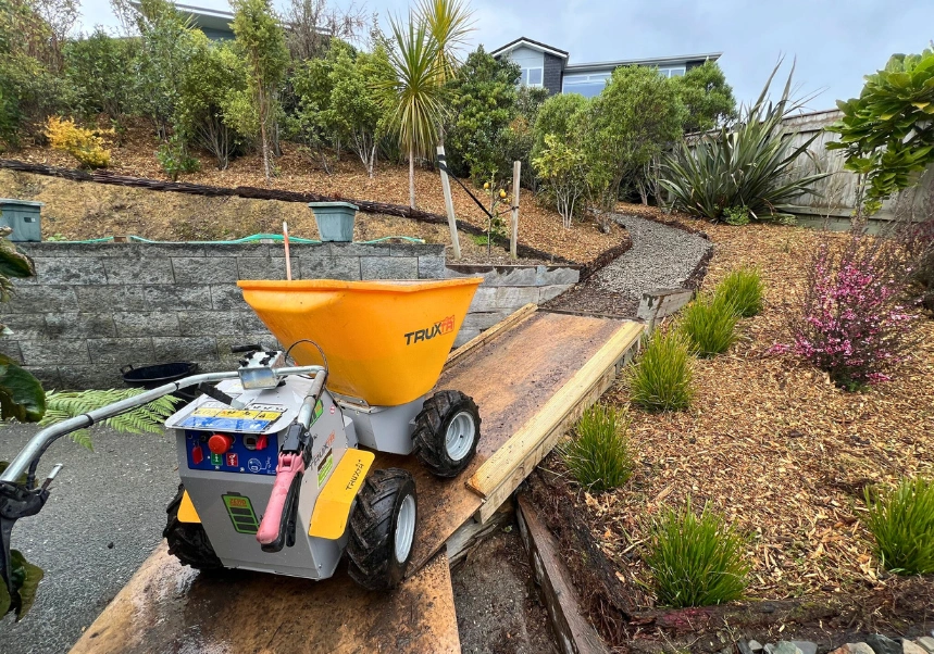 Landscape team moving mulch up ramps to refresh punga logs and replace river stones