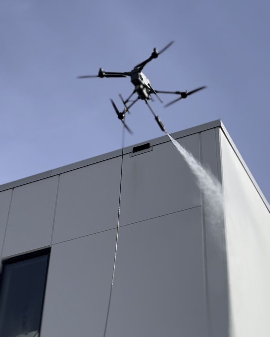 Drone soft-washing the top of a building