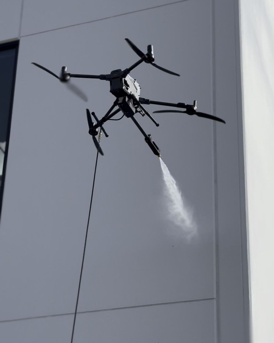 Drone spraying purified water onto a commercial building window