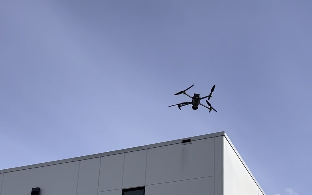 Camera drone flying above a commercial building roofline