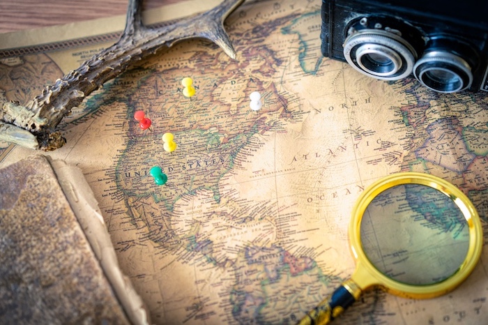 A vintage map with a magnifying glass, camera, and pushpins indicating travel planning - Atlantic Ambience A vintage map with a magnifying glass, camera, and pushpins indicating travel planning - Atlantic Ambience