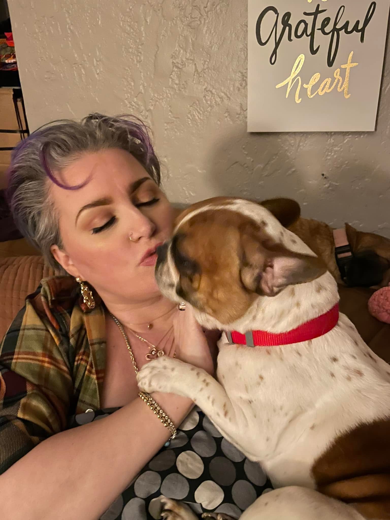 Tiffany at home with her dog under a grateful heart sign