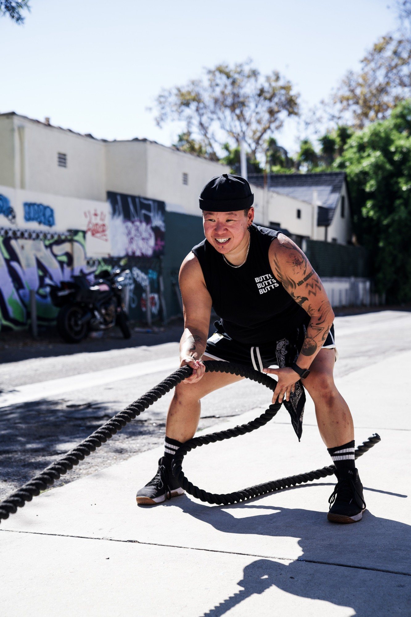 TPE coach Kai smiling through battle ropes outside the gym