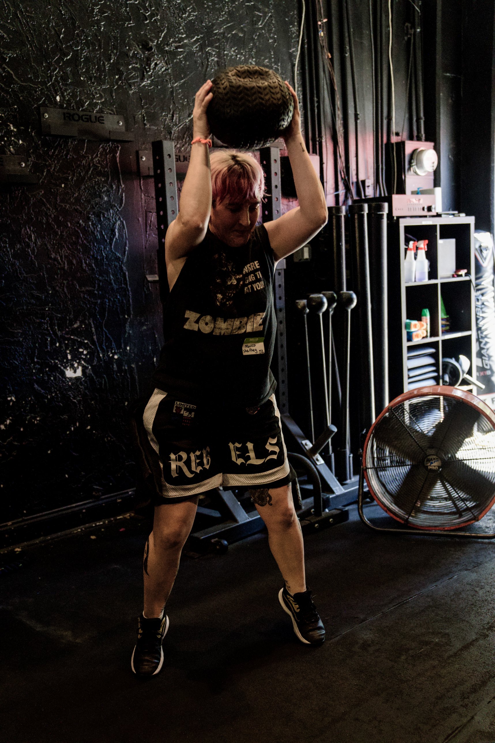 A member lifting a sandbag overhead during strength class at The Phoenix Effect in Hollywood