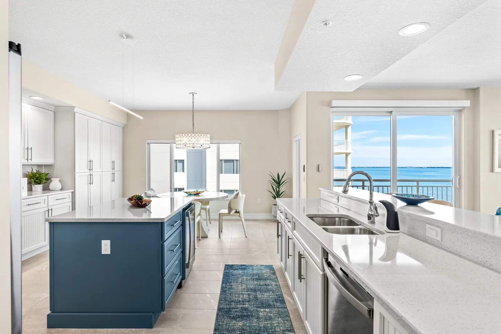 Bright white kitchen with a blue island and waterfront window view