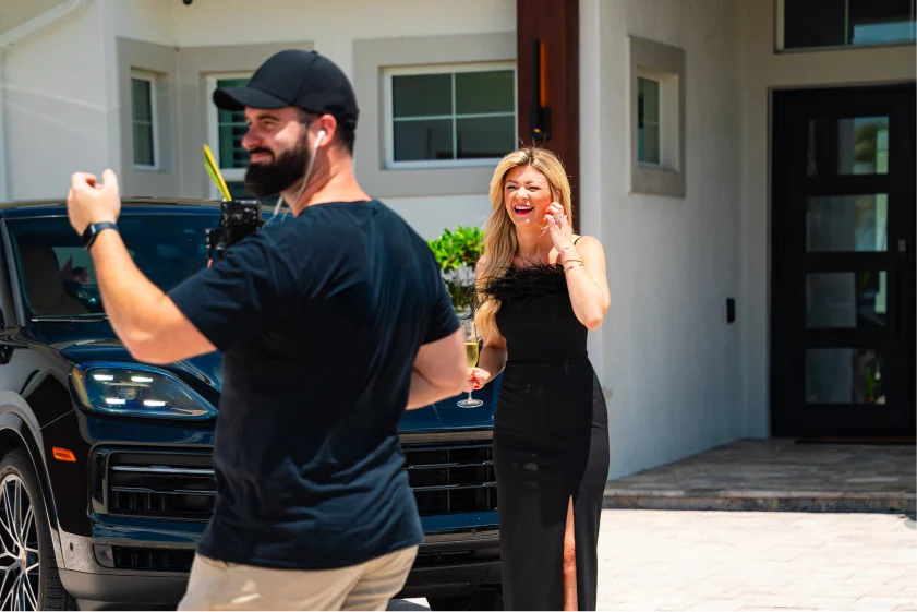 Camera operator filming a woman outside a house