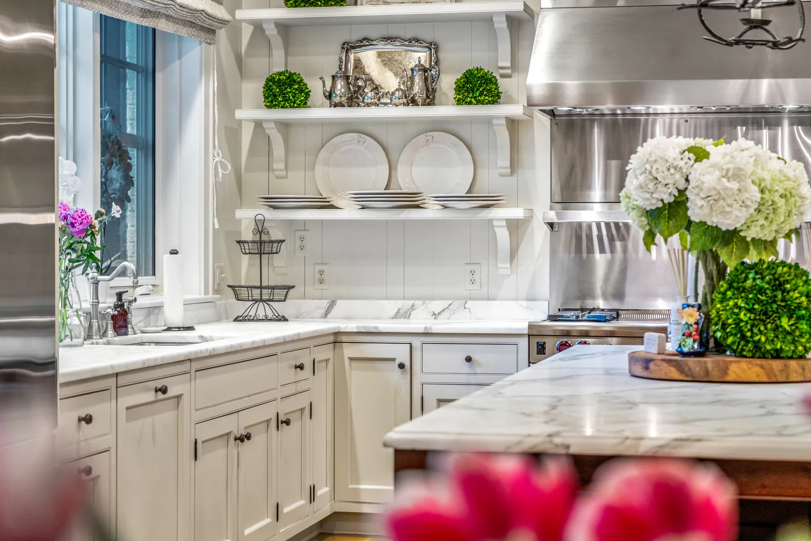 Kitchen detail with marble counters, shelving, and flowers