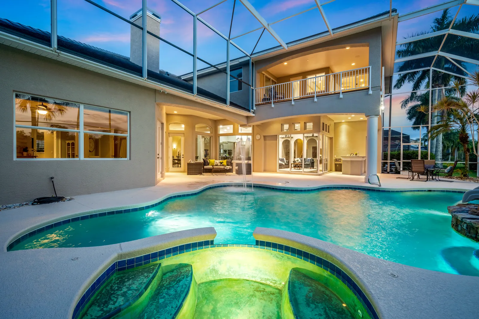 Illuminated pool and warmly lit home under a dusk sky
