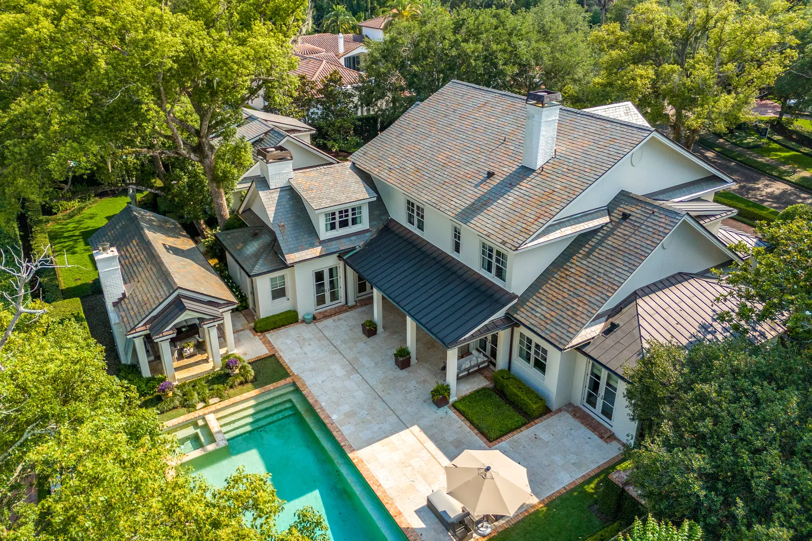 Elevated view of a home, pool, patio, and mature trees