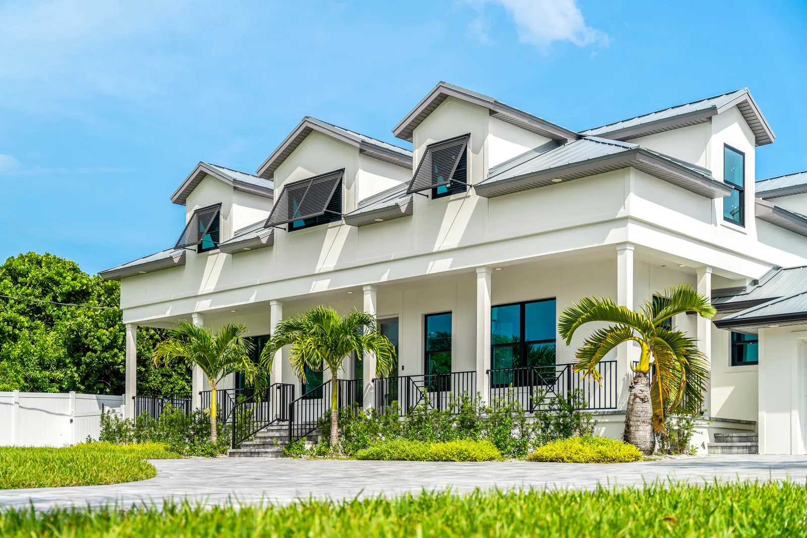 White coastal home with a broad porch and palms