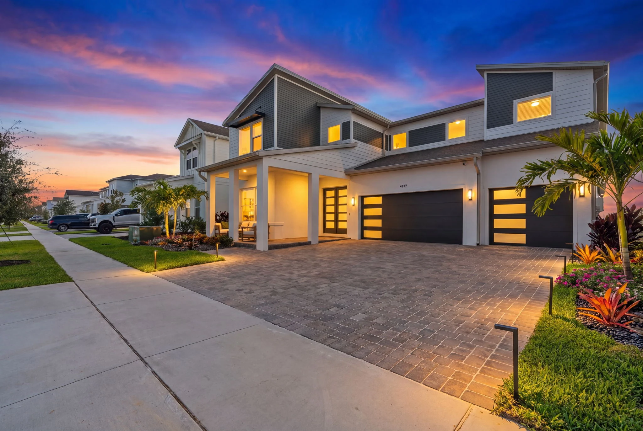 Modern two-story residence with illuminated windows and sunset sky
