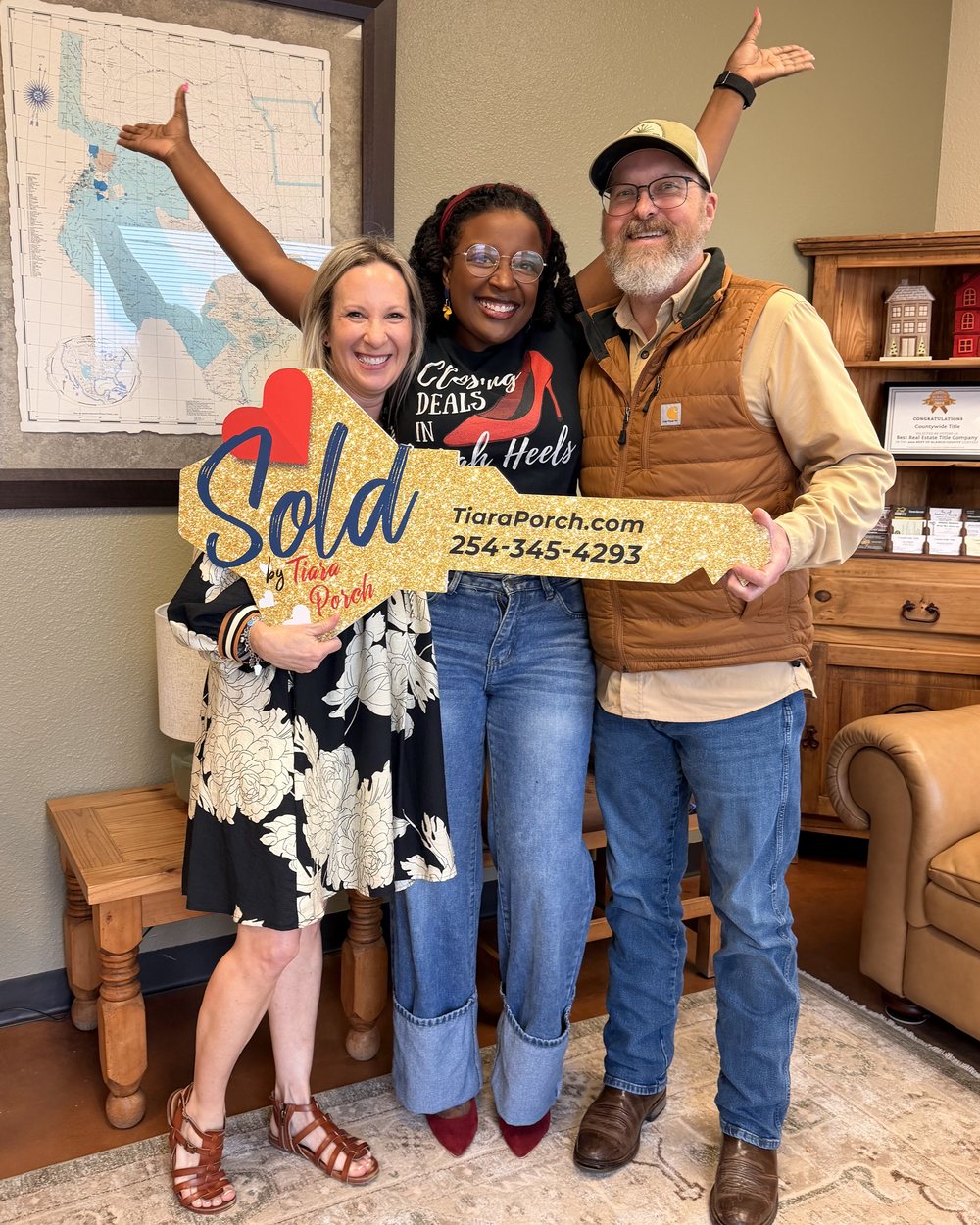 Tiara Porch celebrating with two clients and a Sold sign after closing